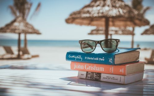 Books and sunglasses with beach in the background