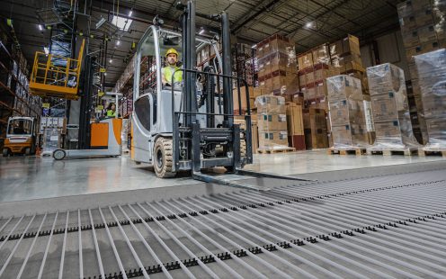 Forklift operator during work in large warehouse with underfloor heating visible